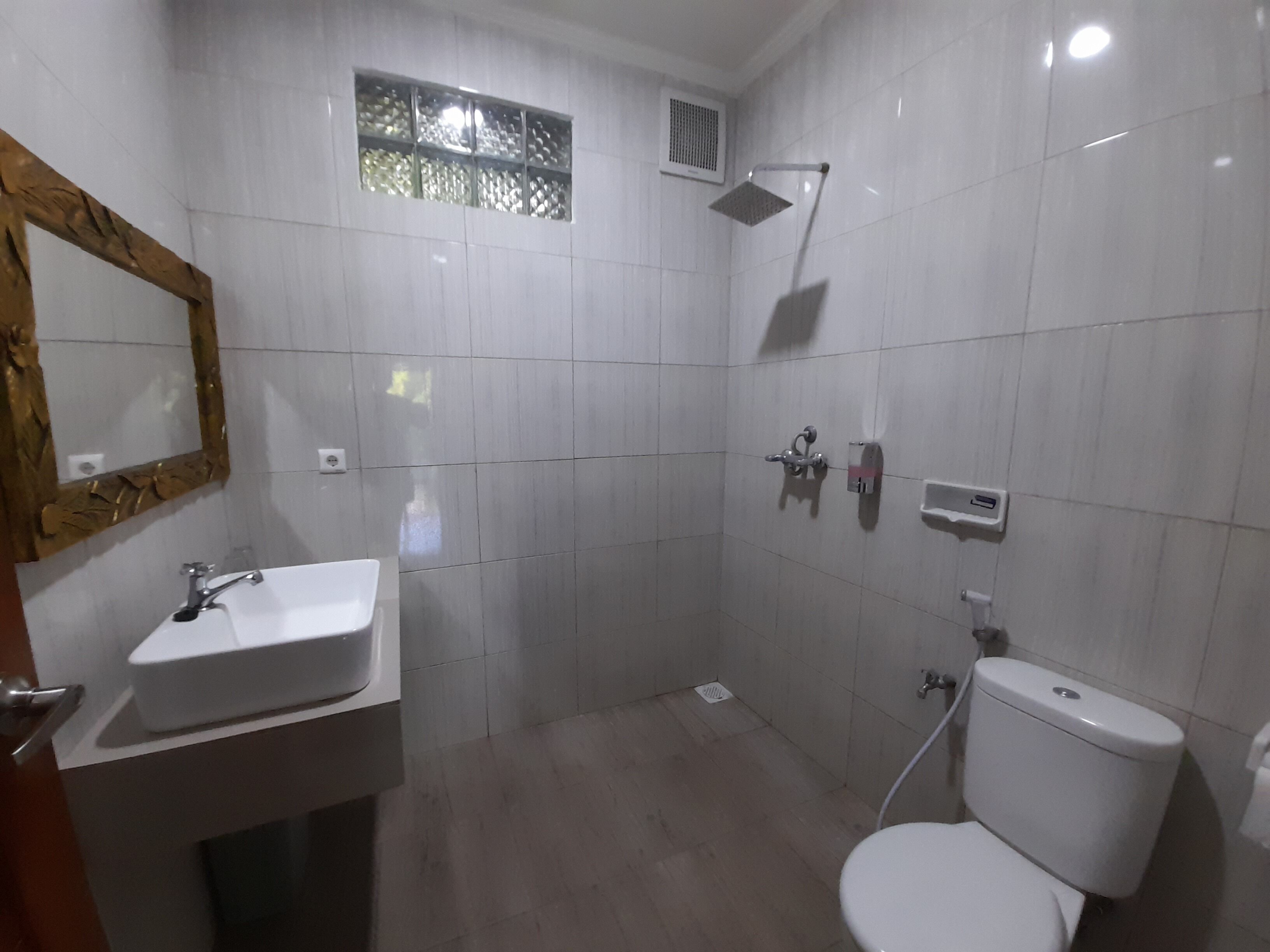 Un baño con lavamanos, inodoro y ducha blancos.