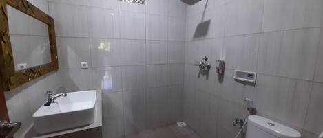 Un baño con lavamanos, inodoro y ducha blancos.