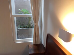 A room with a window, a small table, and a wall-mounted light fixture.