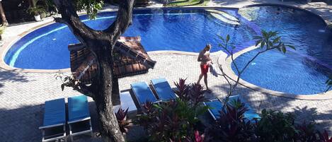 Un área de piscina con sillones de descanso y un árbol.