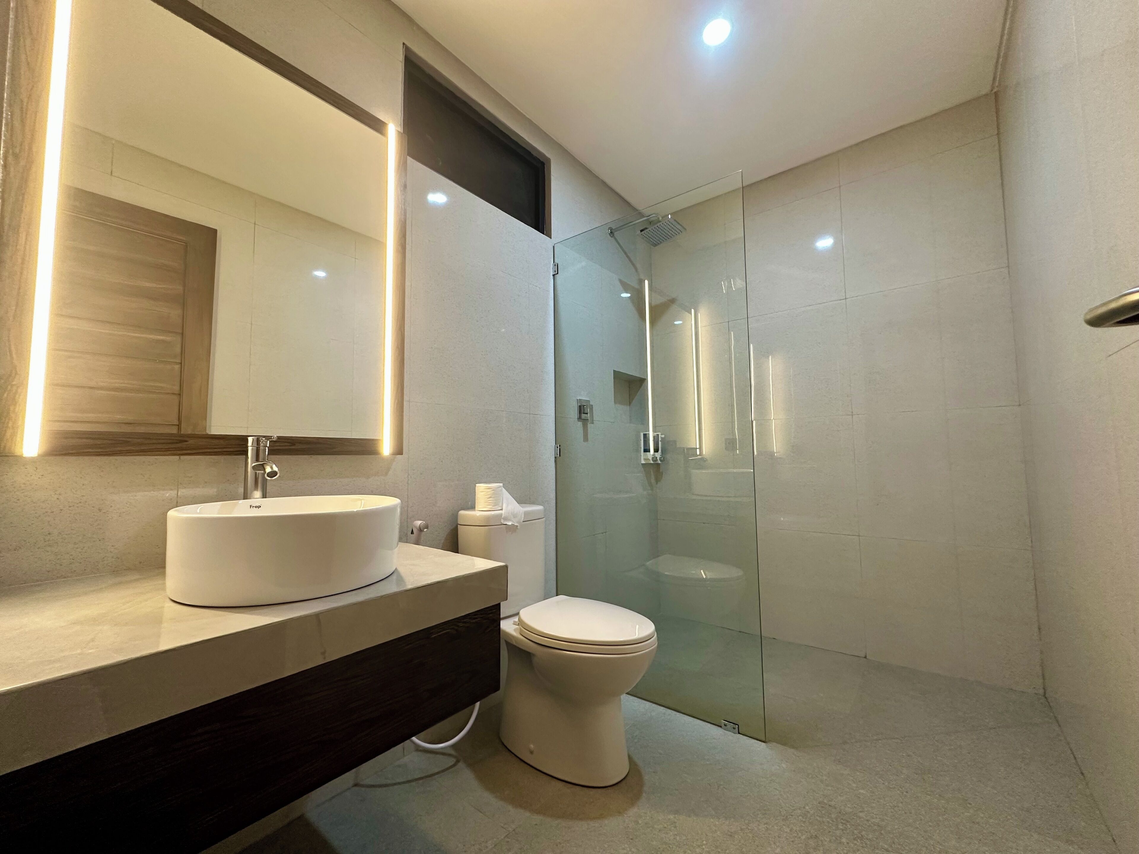 A modern bathroom with a glass-enclosed shower, a white sink, and a toilet.