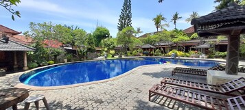 Una piscina al aire libre, sillones reclinables de piscina