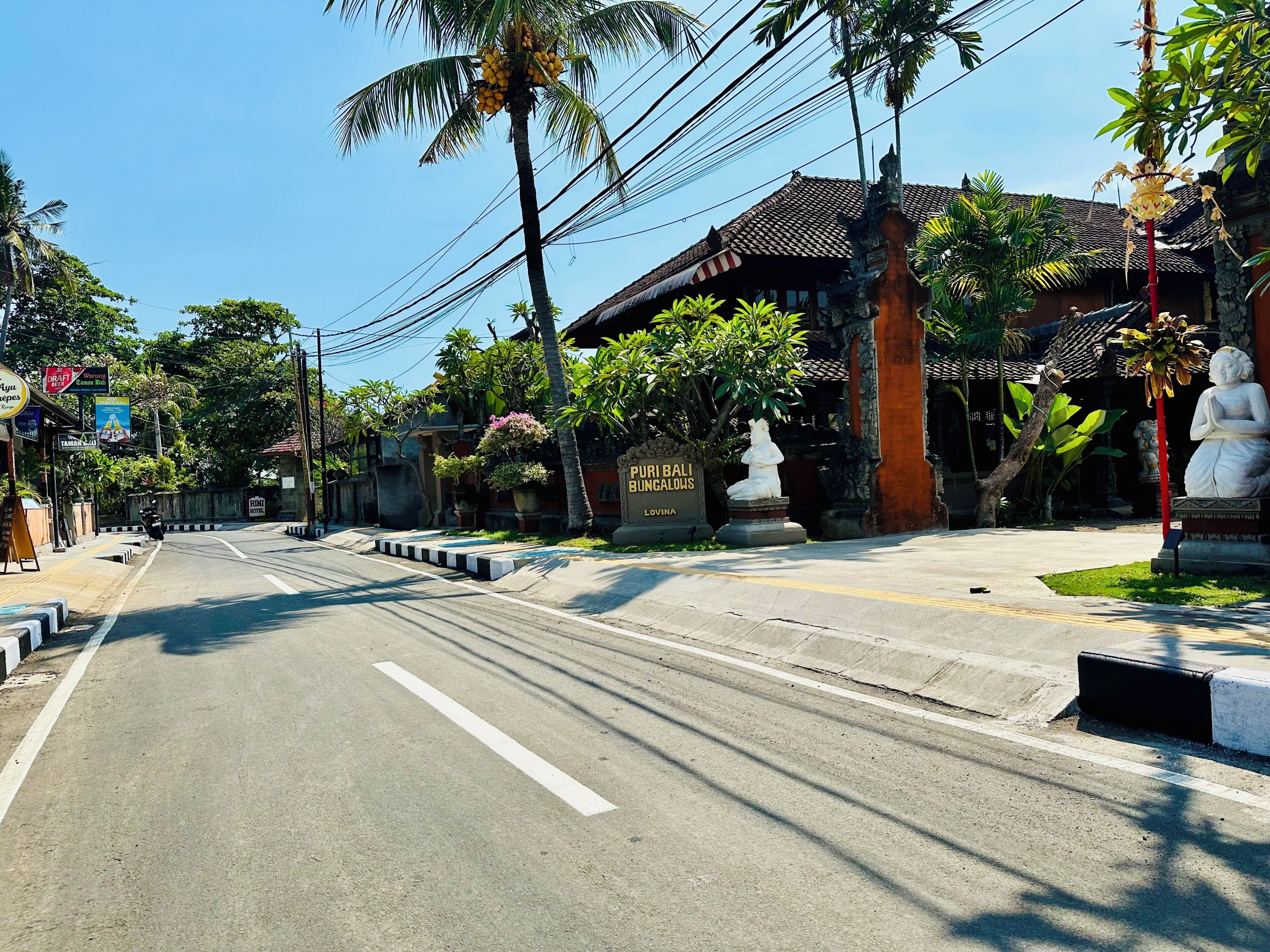 A road leading to a traditional building with a sign reading 'Puri Bali Bungalows.'