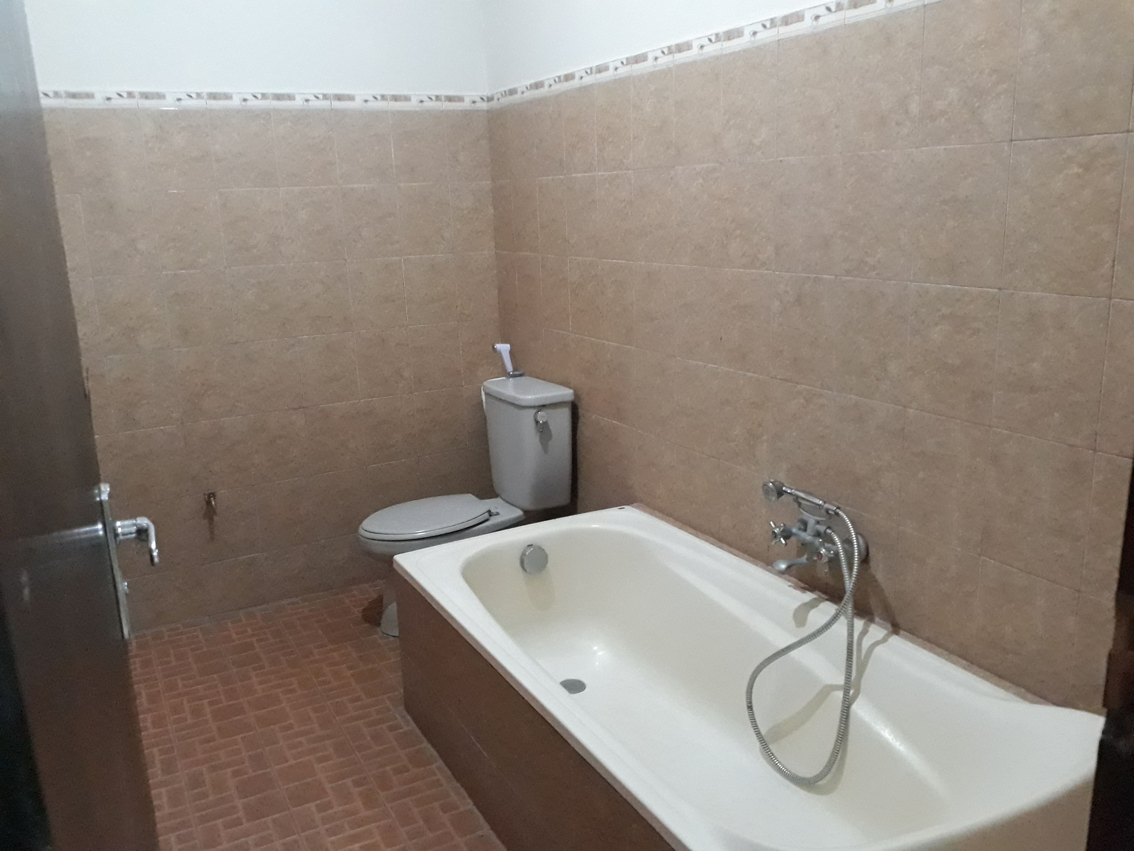 A bathroom with a bathtub, toilet, and tiled walls.