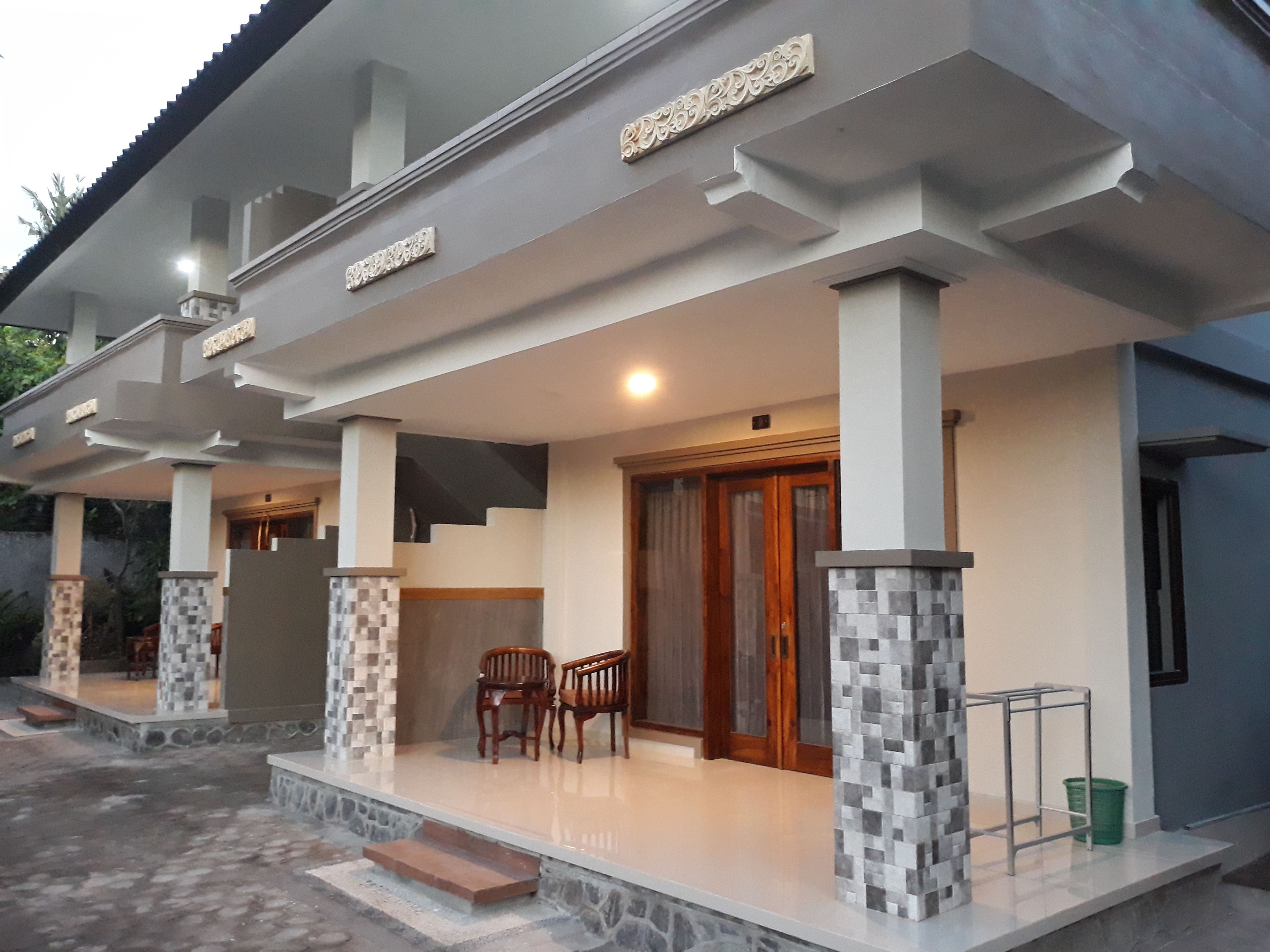 A modern house with a covered porch, two wooden chairs, and a stone-tiled entrance.
