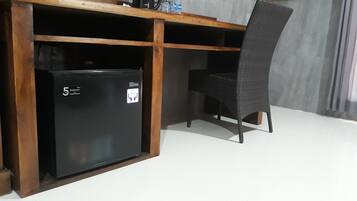 Une petite cuisine équipée avec un réfrigérateur noir, une machine à café et une chaise.