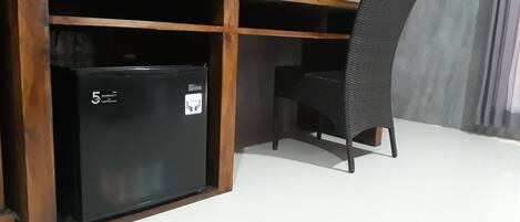 Una kitchenette compacta con un refrigerador negro, una cafetera y una silla.