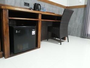 A compact kitchenette with a black refrigerator, a coffee maker, and a chair.