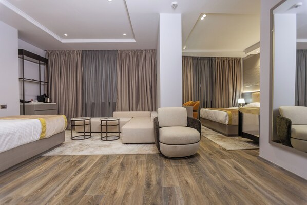 Una habitación de hotel moderna con sofá, sillón y una pequeña mesa redonda.