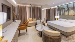 Una habitación de hotel moderna con cama, sofá y zona de comedor.