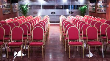 Rows of red chairs with gold frames arranged in a hall with a polished wooden floor.