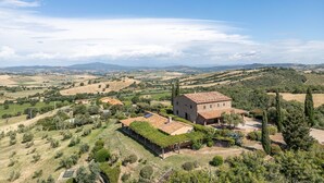 Un paysage rural avec un bâtiment en pierre, entouré de vignes et de collines ondulantes.