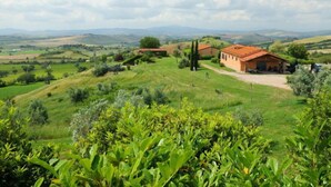 Un paysage rural caractérisé par des collines douces, une ferme et un ciel dégagé.