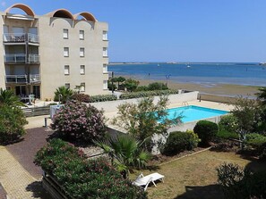 Un hôtel doté d’une piscine, offrant une vue sur la plage et comprenant un bâtiment avec des balcons.