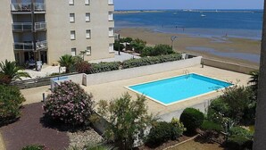Un hotel con piscina, vista al mar y un edificio con balcones.