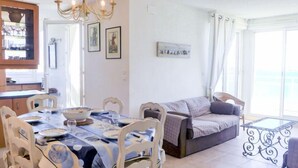 Un comedor con una mesa dispuesta para cuatro personas, un sofá y un balcón con barandilla de hierro forjado.