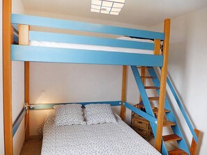 Un lit superposé avec une structure bleue et une échelle en bois.