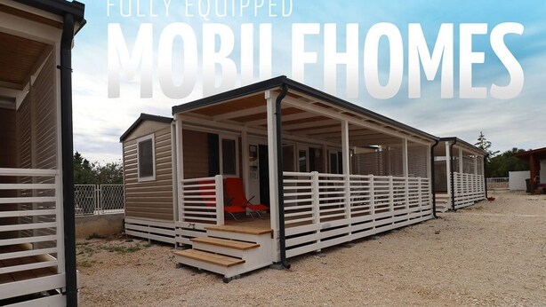 Une maison mobile dotée d’un porche couvert et d’un espace extérieur clôturé.