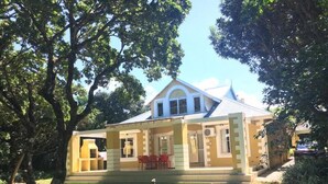 A two-story house with a covered porch and a lawn. - Caribbean Estates Villa & Apt (Port Edward)