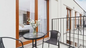 A balcony with a glass table and chairs, a white sofa, and a vase with flowers. - Cracow | Rakowicka 22J | Intimate Studio | Air Conditioning (Kraków)