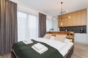 Una habitación de hotel moderna con una cama grande, una kitchenette y vistas a la ciudad.