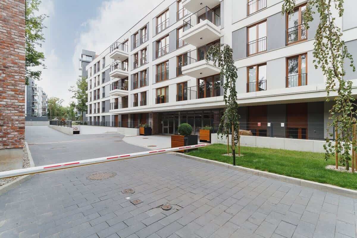 Moderni, useita kerroksia sisältävä asuinkerrostalo, jossa on parvekkeet, kivetty sisäpiha ja vasemmalla puolella tiiliseinä.
