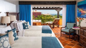 Une chambre d’hôtel avec deux lits, une chaise, une table et vue sur l’océan.