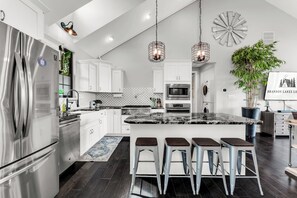 A modern kitchen with stainless steel appliances, a marble island, bar stools, and pendant lighting. - Private Pool Paradise/Luxury Home Stunning Table Rock Lake Views/Branson Close (Branson)