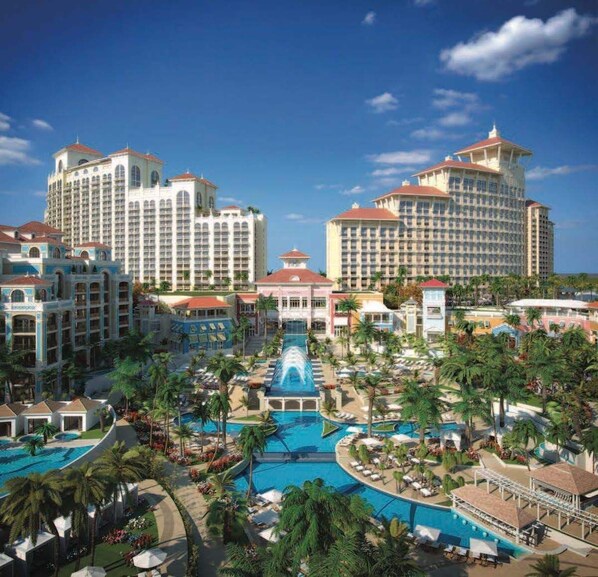 A resort with multiple high-rise buildings, a central swimming pool, and palm trees.