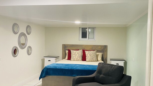 Een slaapkamer met een bed, een stoel, een raam en decoratie aan de muur.
