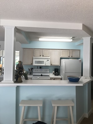 Effortlessly cook and dine in this well-equipped kitchen with a central island, microwave, stove, refrigerator, and coffee maker.