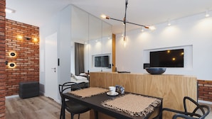 A modern dining area with a wooden table, black chairs, and a black countertop with a bowl. - Wooden Studio with Balcony | Parking | Close to Station (Kraków)