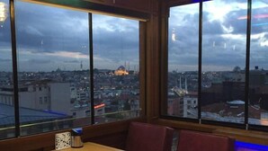 A restaurant with a view of a cityscape, featuring a table and booths, and a colorful ceiling. - Medar Hotel (Istanbul)