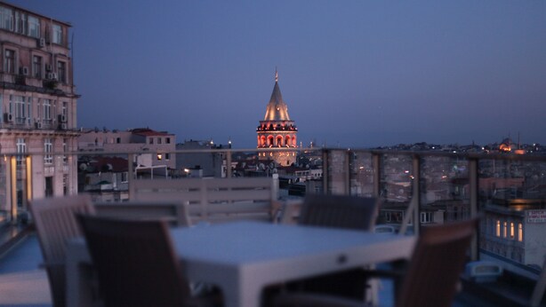 A dining area with a table and chairs, overlooking a cityscape with a prominent building with a pointed roof. - Medar Hotel (Istanbul)