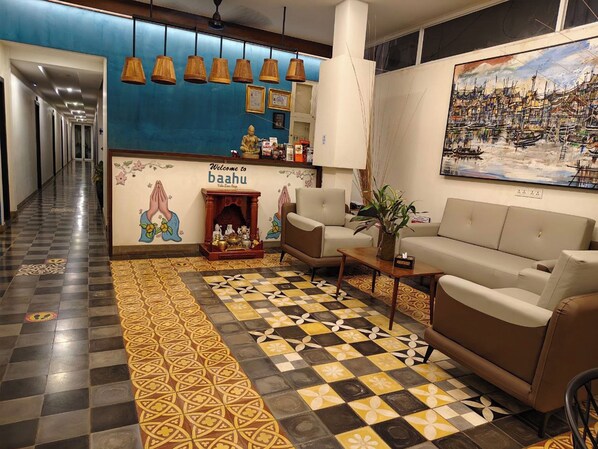 A hotel lobby with a checkered floor, a sofa, a fireplace, and a wall with a painting. - Baahu Villa (Siem Reap)