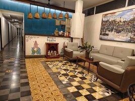 Um saguão de hotel com piso xadrez, um sofá, uma lareira e uma parede com um quadro.