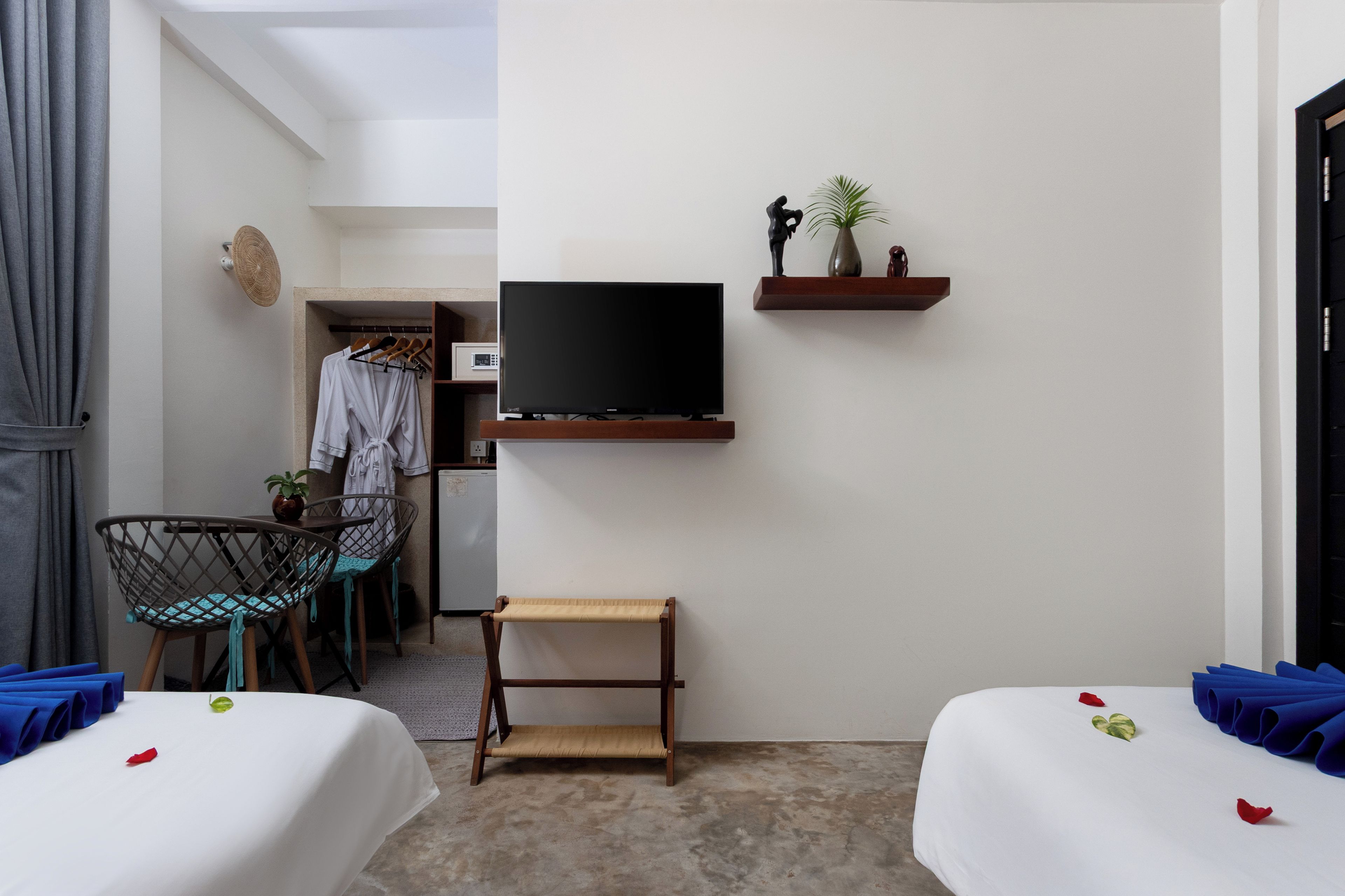 Une chambre d’hôtel de taille réduite, comprenant un lit, une petite table, une chaise, un téléviseur et une armoire.