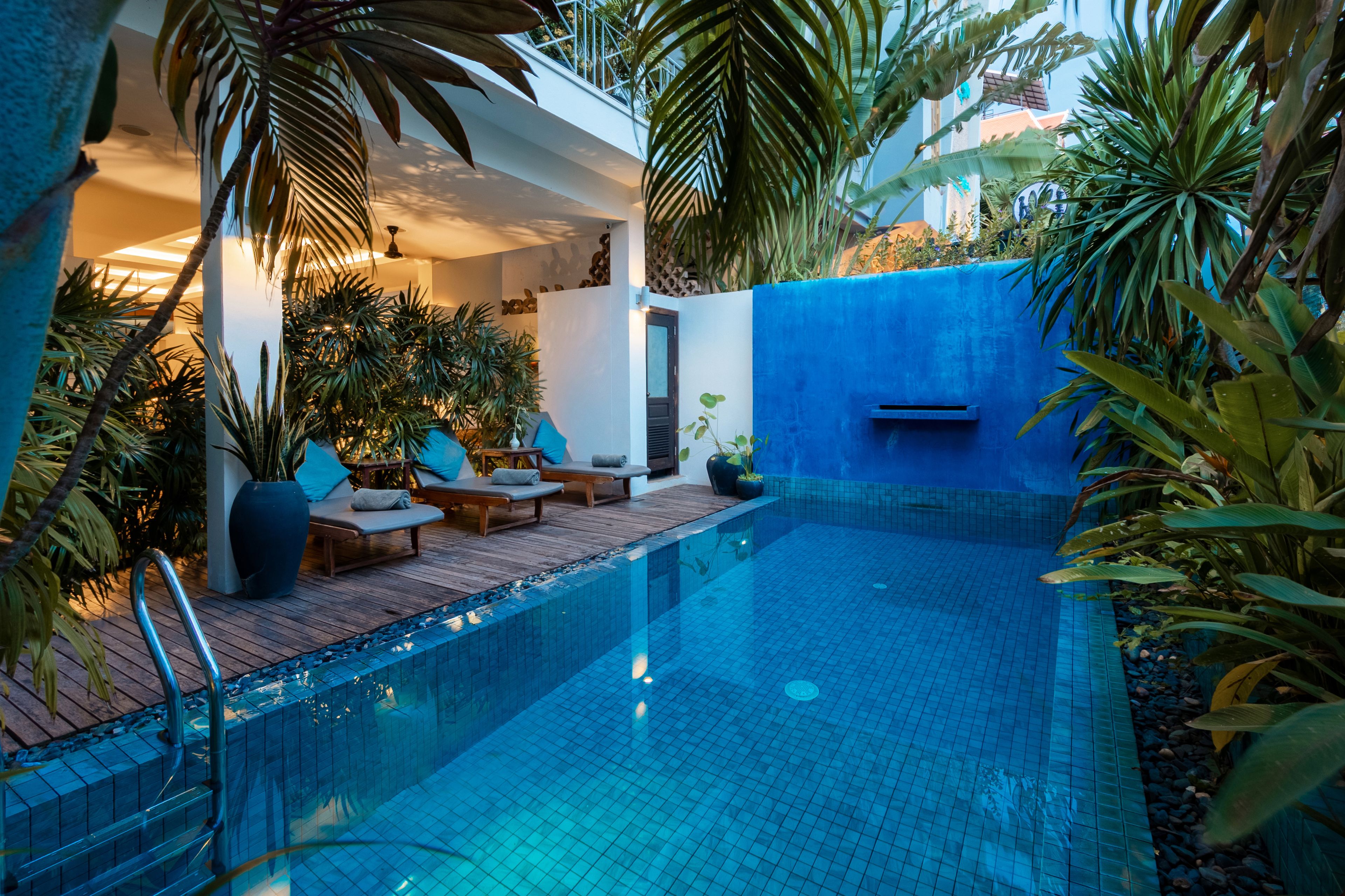 A pool area with lounge chairs and a blue wall.