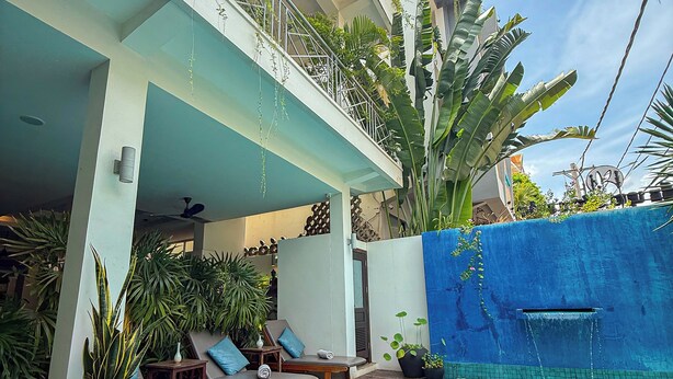 A poolside area with lounge chairs, a wooden deck, and a blue-tiled pool. - Baahu Villa (Siem Reap)