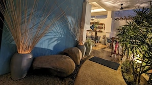 A modern interior with a blue wall, large potted plants, and a seating area with a table and chairs. - Baahu Villa (Siem Reap)