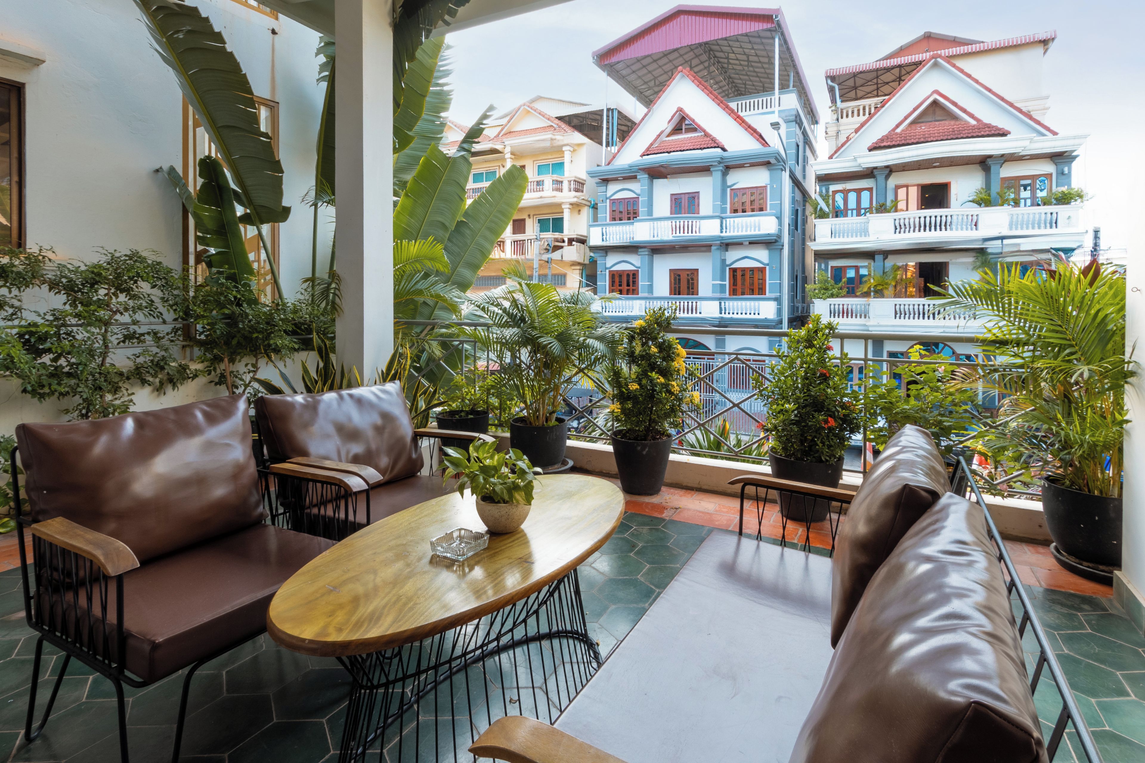 A terrace with a seating area, potted plants, and a view of colorful buildings.