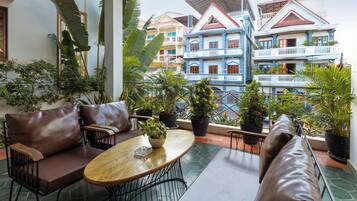 A terrace with a seating area, potted plants, and a view of colorful buildings.