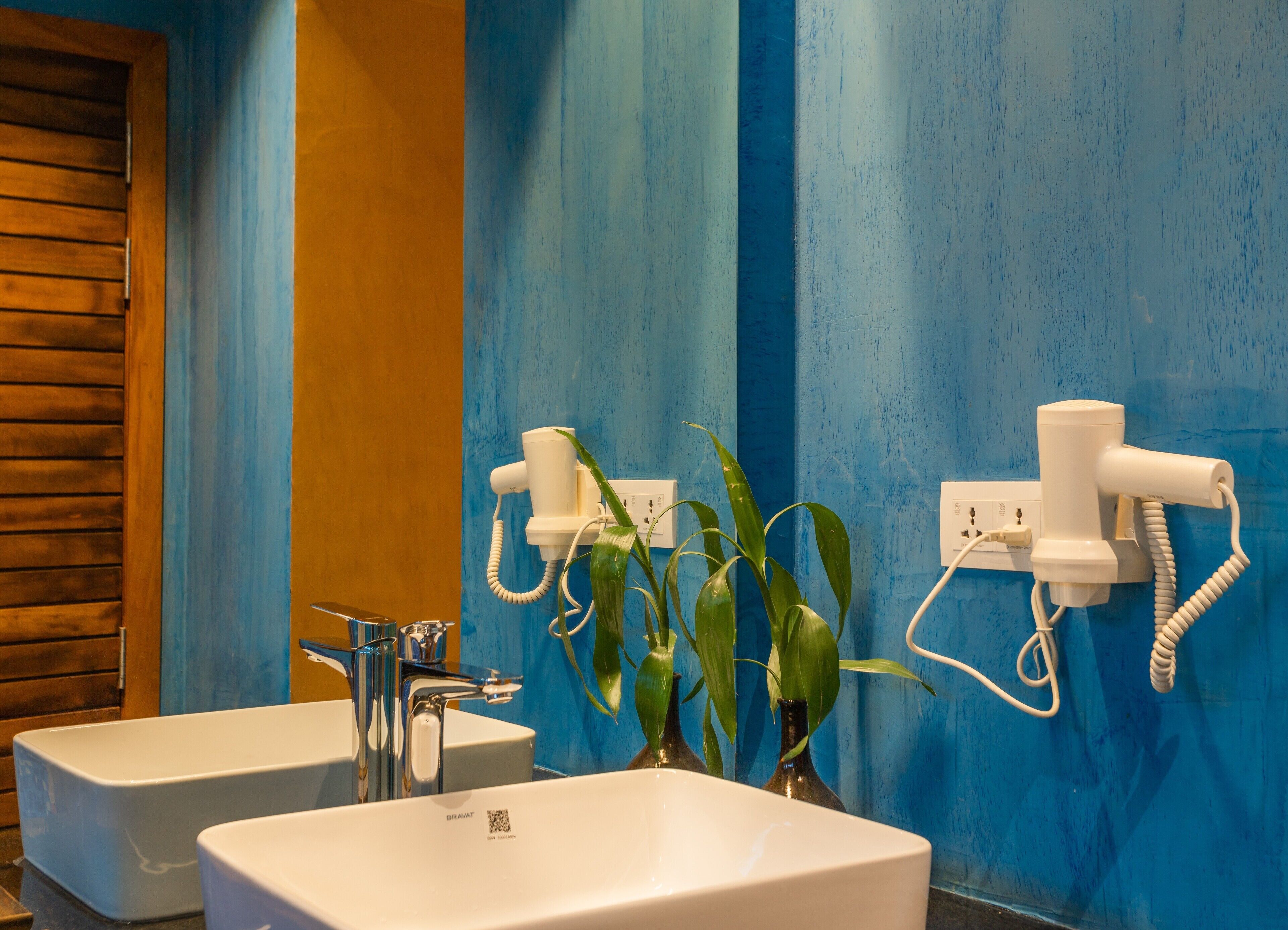 A bathroom with two sinks, a mirror, and a hairdryer mounted on the wall.