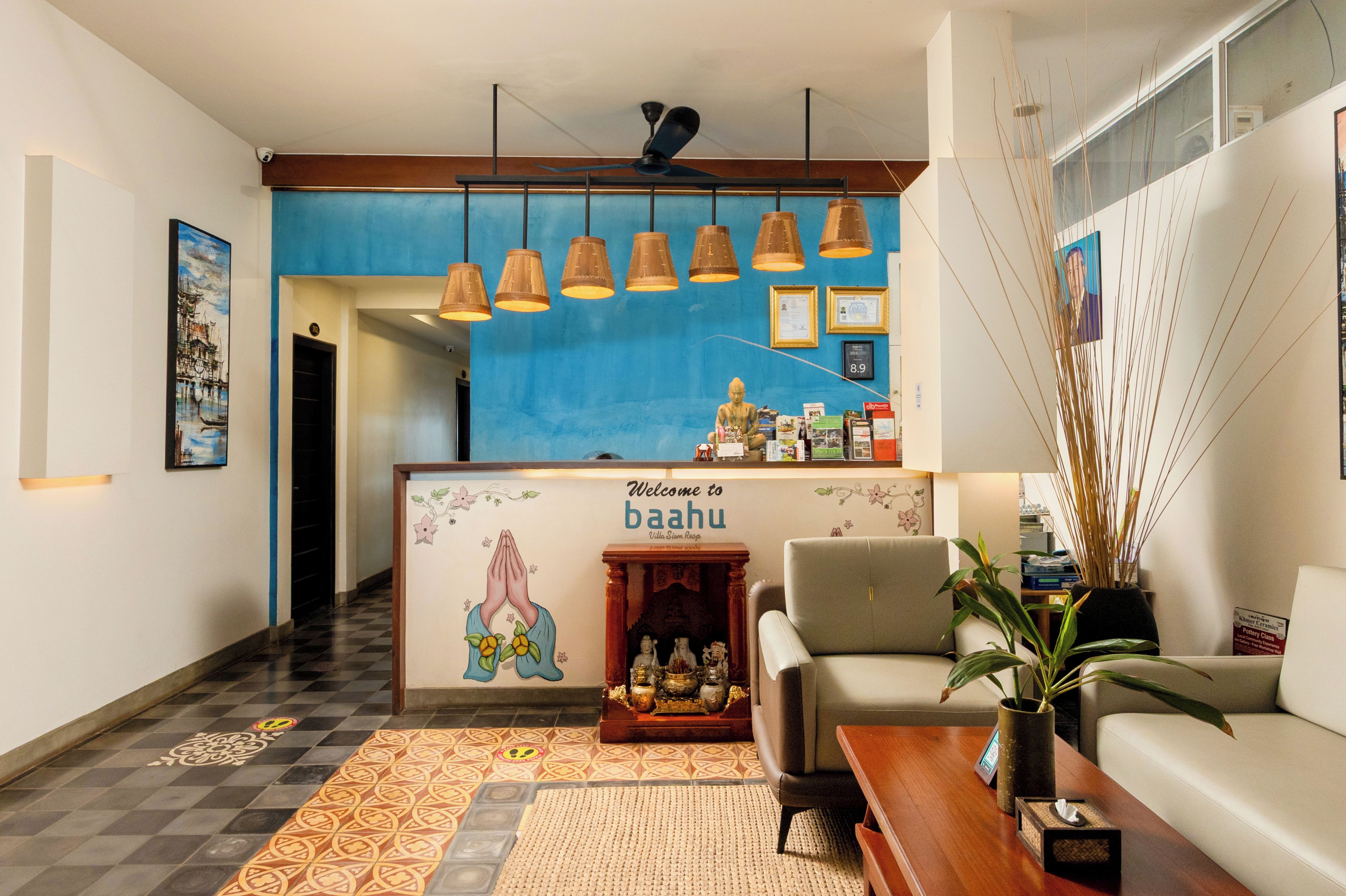 Un área de recepción con pared azul, un cartel de bienvenida, un sofá, una mesa de centro y un altar decorativo.