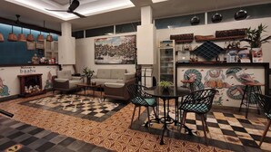 A modern interior with a checkered floor, a sofa, a dining table with chairs, ceiling fans, and a wall with a cityscape painting. - Baahu Villa (Siem Reap)