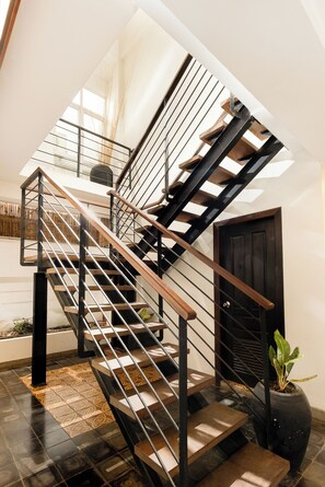 A modern staircase with a wooden handrail and metal balusters, leading to an upper floor. - Baahu Villa (Siem Reap)