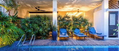 Una piscina interior con sillones de descanso y plantas en macetas.