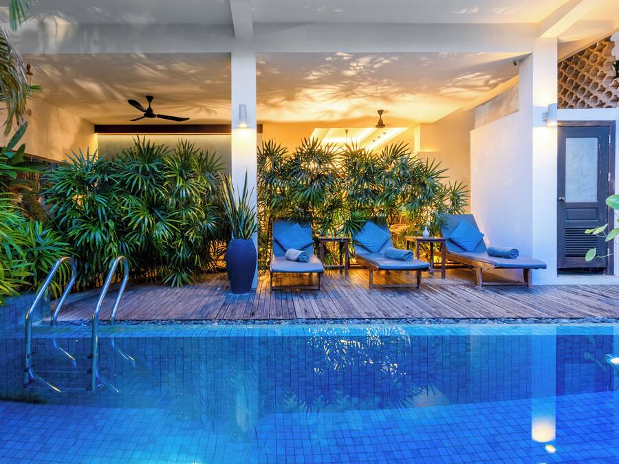Piscina interna com espreguiçadeiras e plantas em vasos.