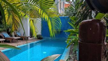 A swimming pool surrounded by lush greenery and a blue-tiled deck.