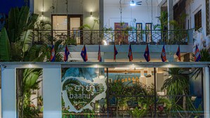 A modern building with a balcony, flags, and a sign with a heart shape. - Baahu Villa (Siem Reap)